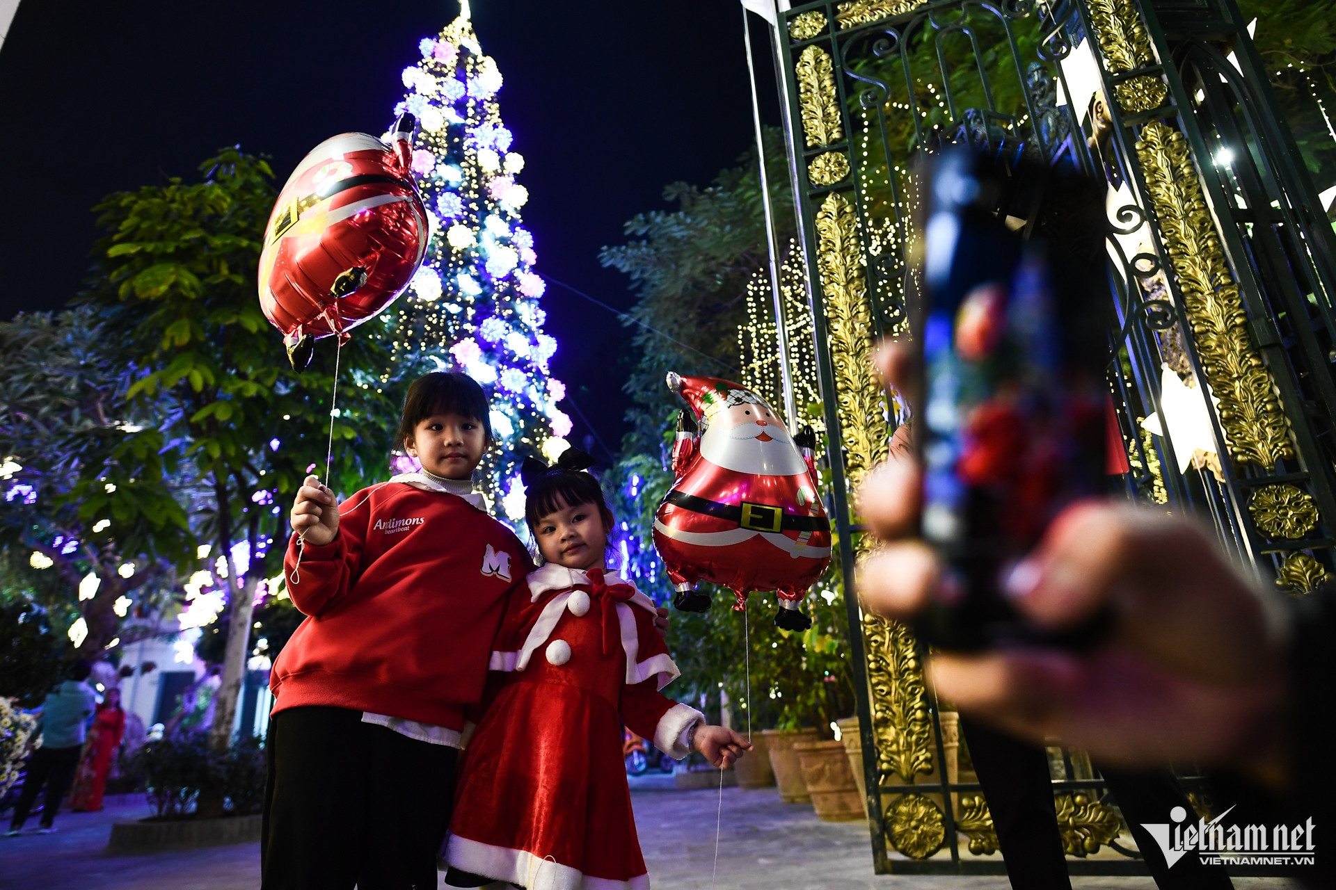 Chun và Chin diện trang phục màu đỏ cầm theo bóng bay ông già Noel cùng bố mẹ đến nhà thờ Hàm Long chơi tối. Hai chị em thích thú khi được bố chụp ảnh kỷ niệm cho bên cạnh cây thông Noel lớn.