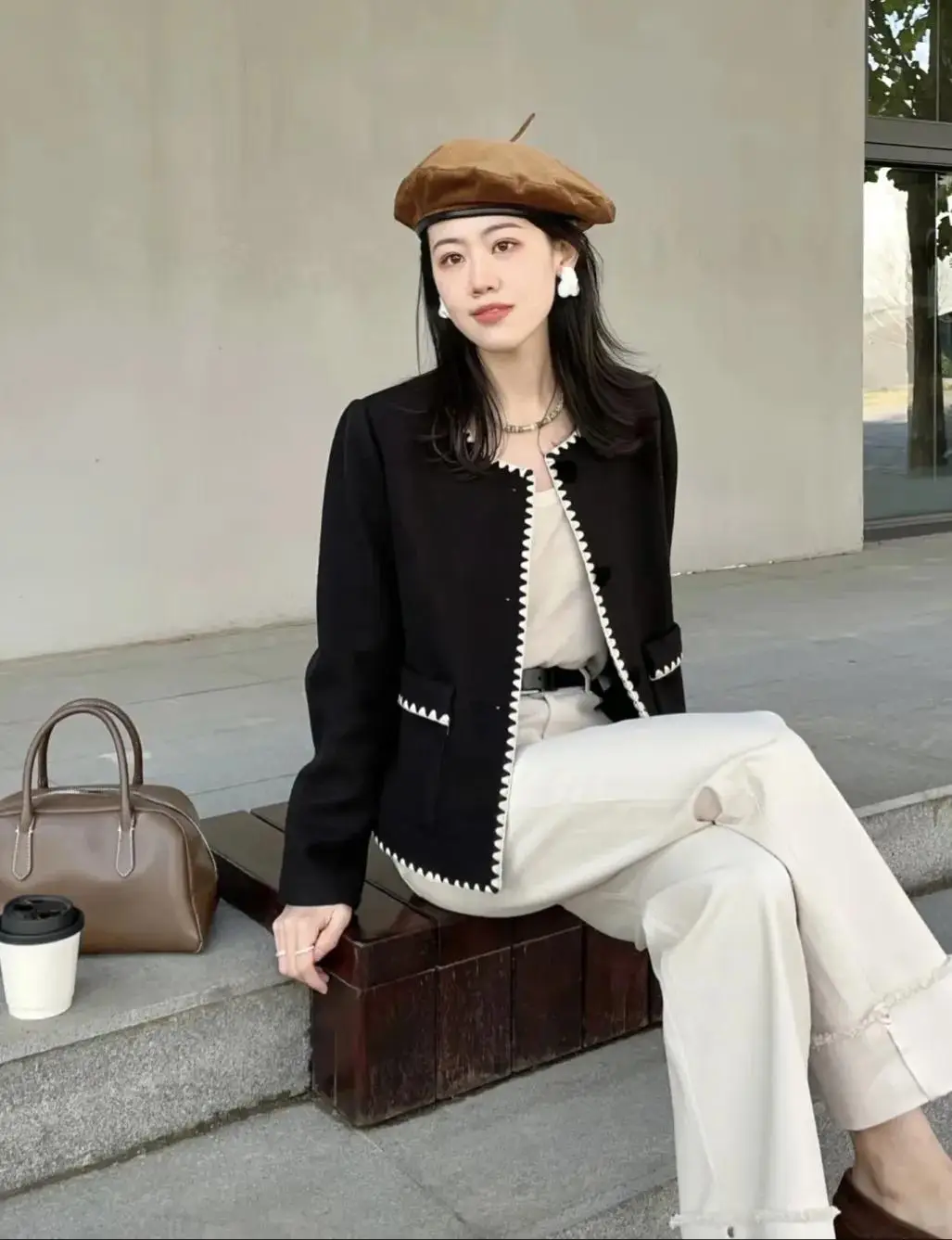 Mặc một chiếc áo khoác vải tweed màu đen, bên trong là set đồ trắng tinh giản và sáng sủa, chị em có thể điểm thêm chiếc túi xách và mũ cùng màu nâu để thể hiện sự sang trọng và thời trang của bạn.