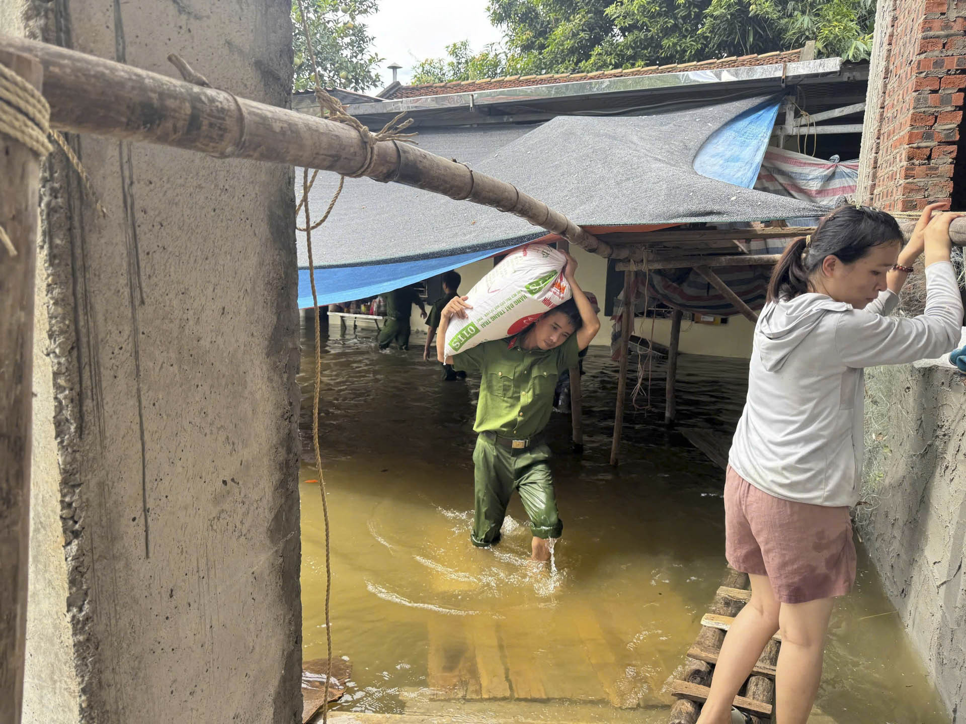 Công an xã Tân Yên lội nước lũ, hỗ trợ người dân di dời tài sản.