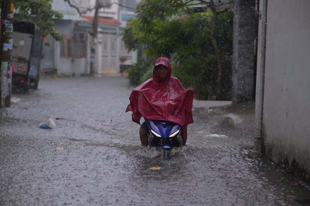 Nước từ kênh tràn ra đường hẻm 218 khiến khu vực ngập hơn bánh xe, ảnh hưởng lớn đến việc đi lại của người dân. Ảnh: PHẠM HẢI