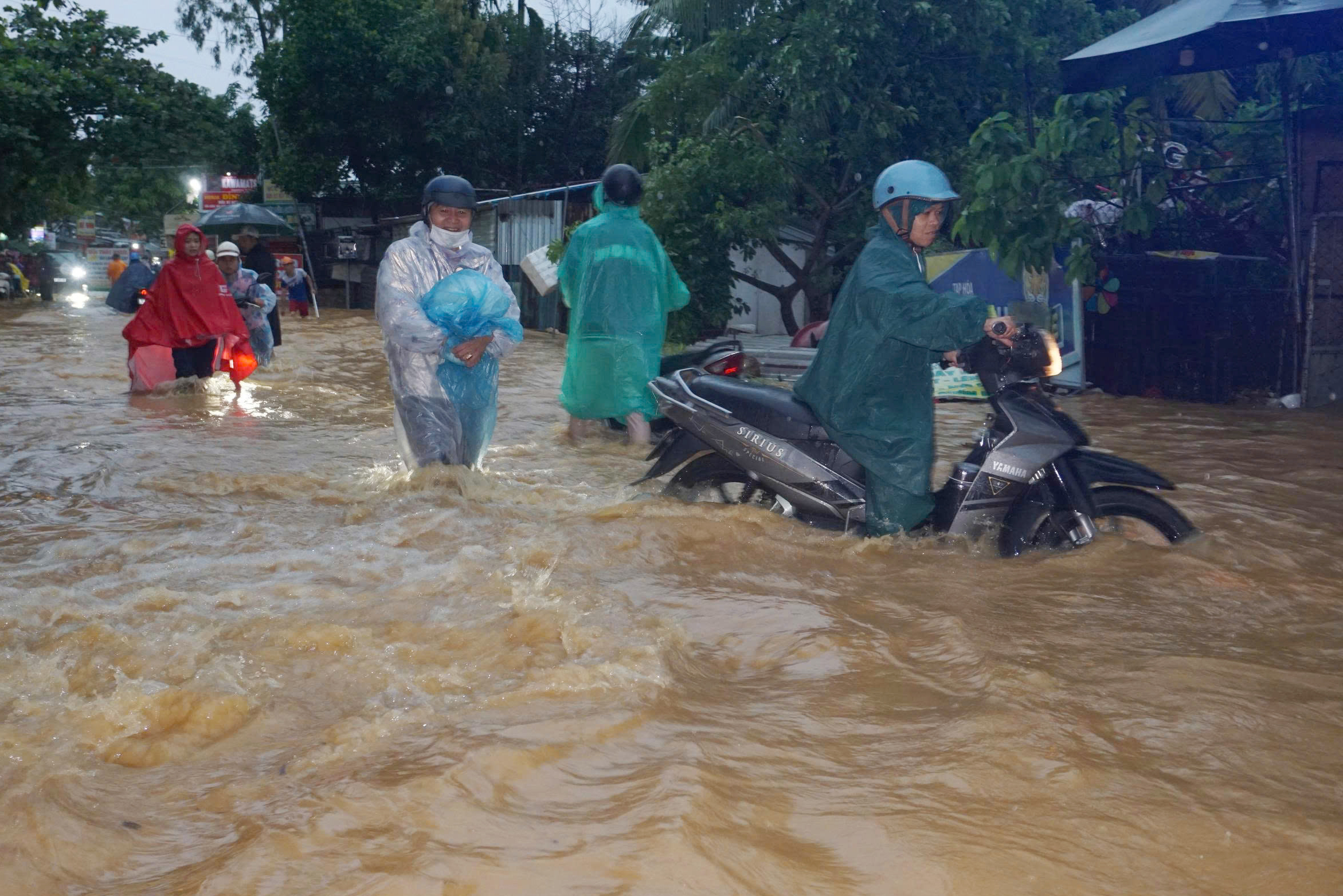 Hàng trăm xe máy đi qua khu vực này bị chết máy, nhiều người bị cuốn ngã khi cố băng qua dòng nước.