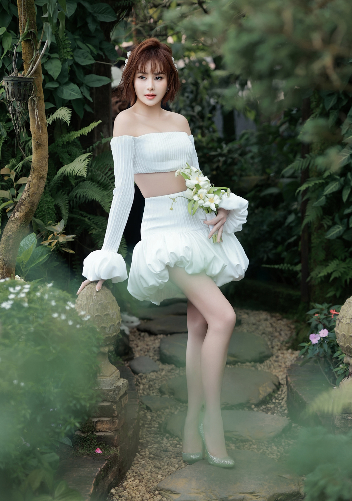 Sella Trương phô diễn thế mạnh hình thể với chân dài, eo thon, vai trần trong thiết kế crop-top phối chân váy xòe bằng chất liệu vải dệt gân.