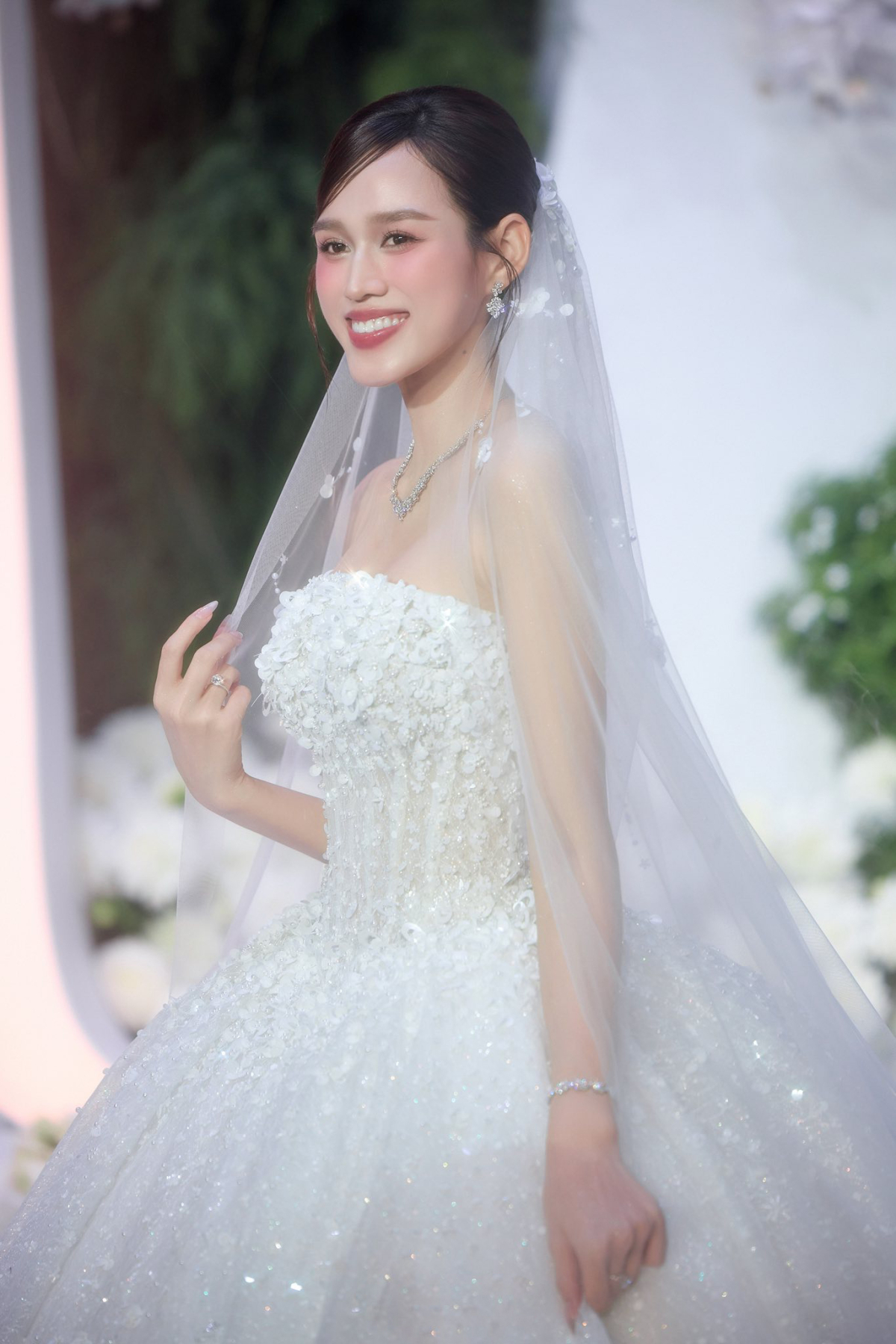 Chiếc Ball Gown cổ điển với corset 10 lớp ép nhiệt ôm trọn dáng vóc của nàng hậu. Toàn bộ bề mặt váy được đính kết bằng hoa 3D và hạt pha lê chuyển sắc, tạo nên hiệu ứng lấp lánh theo từng bước chân.