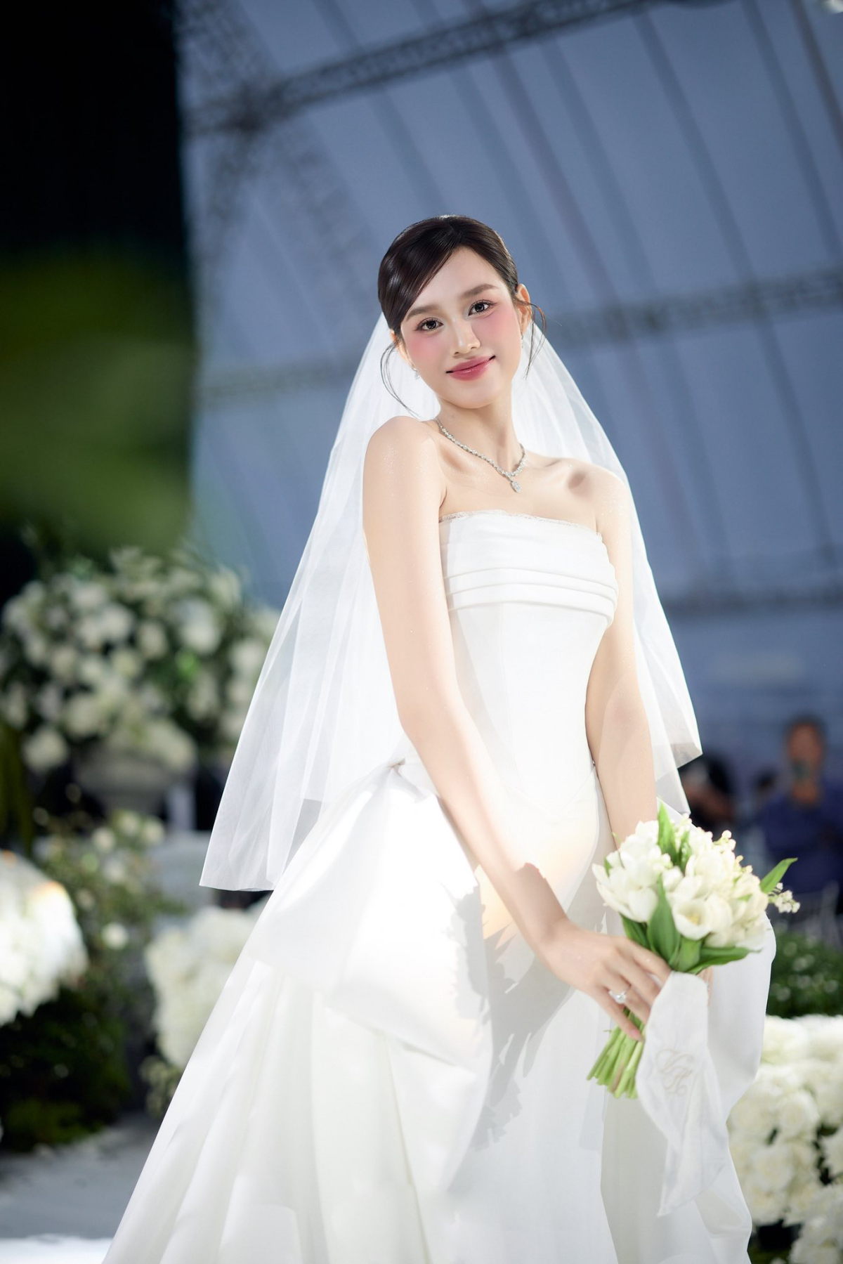 Với chi tiết áo cúp ngực, NTK điểm xuyết đường ren mỏng nhẹ nơi viền ngực vừa tạo cảm giác mềm mại, vừa giữ được nét thanh lịch, tinh khôi cho nàng hậu.