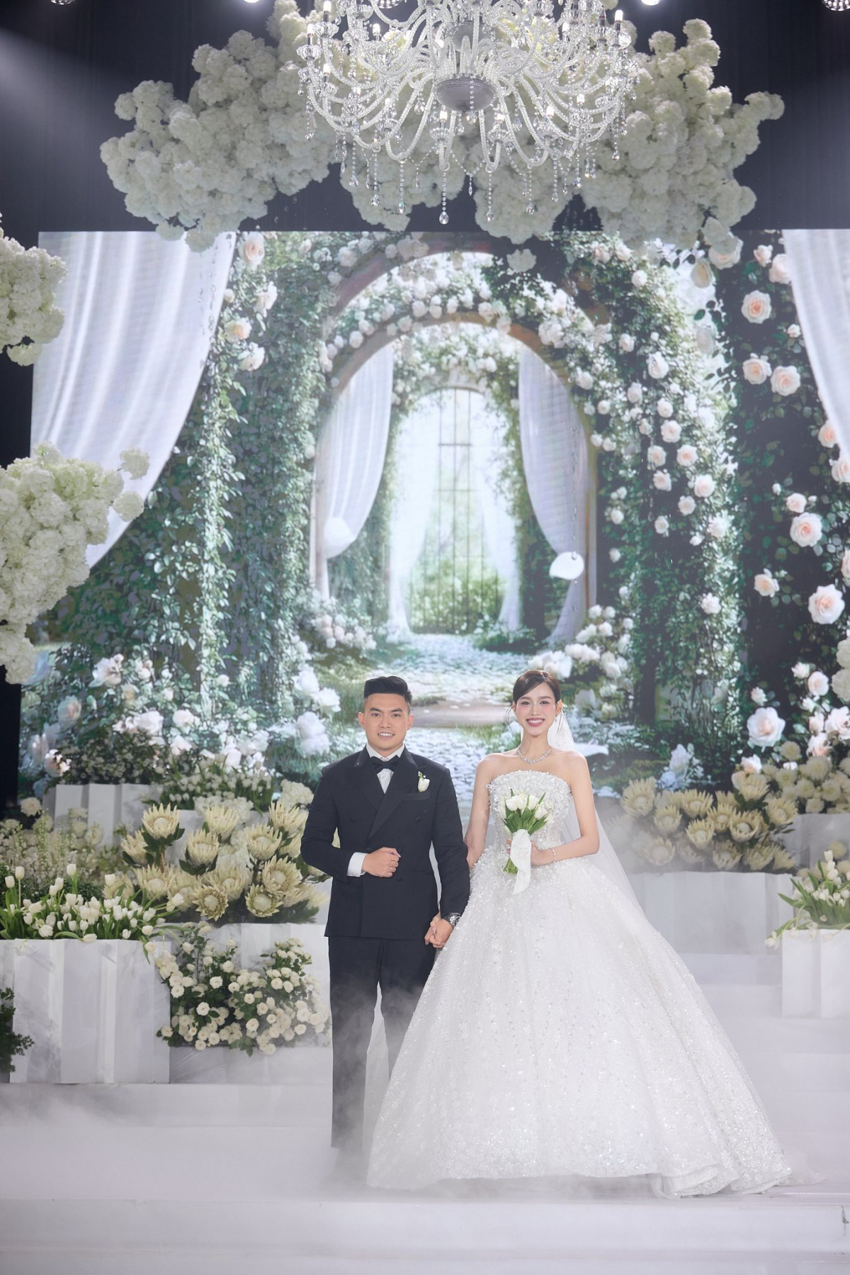 Sau khi chào khách, Đỗ Thị Hà thay chiếc váy cưới thứ hai để thực hiện các nghi lễ chính của buổi tiệc. Bộ đầm lộng lẫy The Bloom of Light được NTK Trà Linh cùng đội ngũ mất hơn hai tháng sáng tạo riêng và chế tác thủ công.