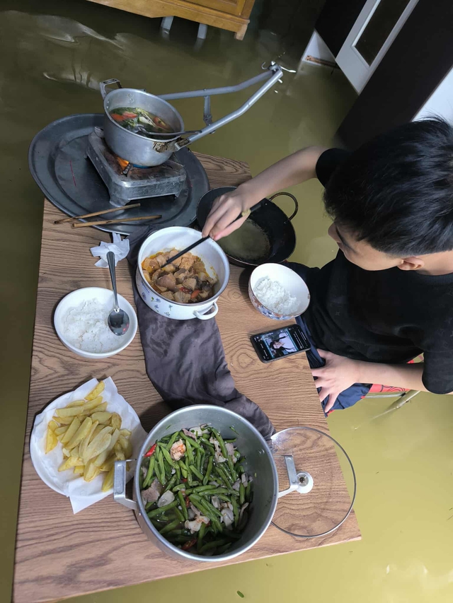 Mỗi ngày triều cường xảy ra 2 lần, trong đó một lần vào buổi trưa và một lần vào đêm khuya, kết hợp với nước lũ đã khiến cho khu dân cư này ngập sâu trong 2 ngày qua. Và đây là bữa cơm của một nam thanh niên trong khi triều cường lên.