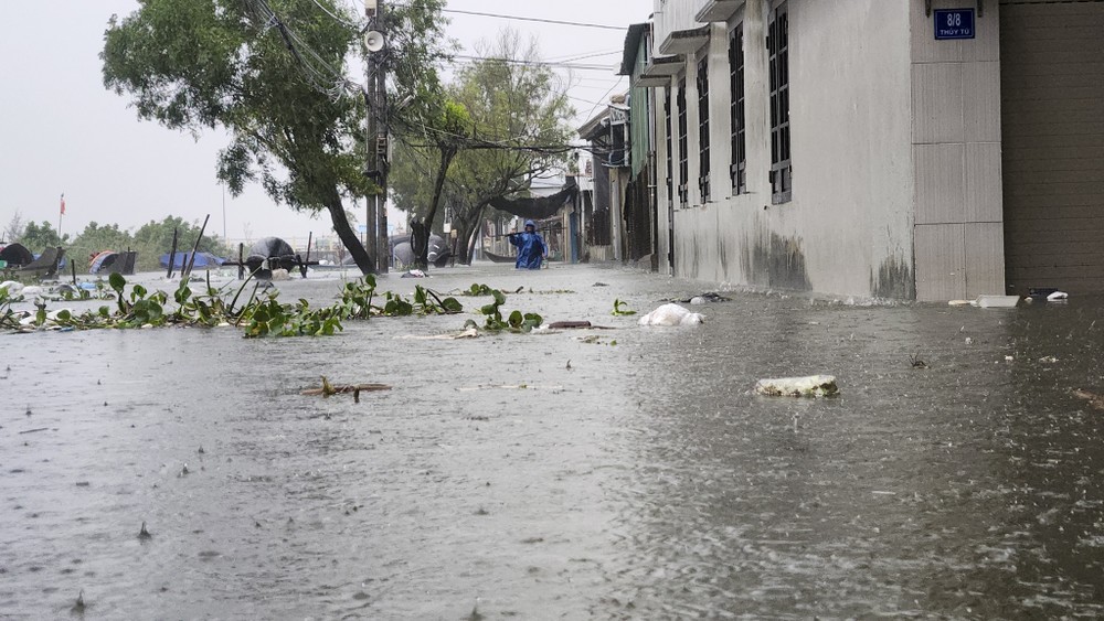 Người dân vật lộn trong dòng nước lũ. Ảnh: NGUYỄN DO