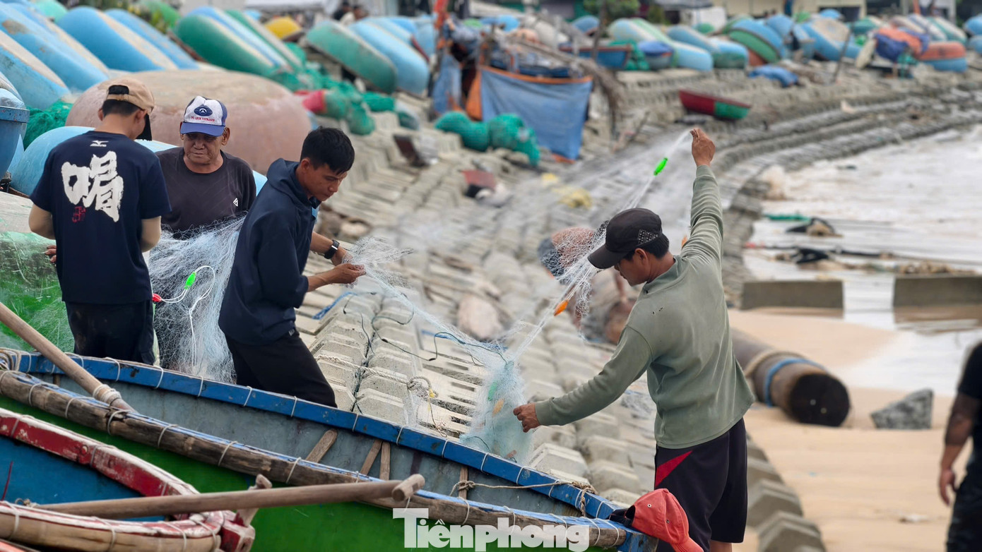Cách đó không xa, ngư dân Trương Văn Vệ cũng vừa đưa thúng về bờ, tay thoăn thoắt gỡ cá khỏi lưới. “Biết là nguy hiểm, sóng lớn do ảnh hưởng áp thấp nhiệt đới. Nhưng tụi tôi chỉ đánh bắt gần bờ thôi, khoảng một hải lý. Lúc này cá về nhiều, không đi thì tiếc. Nay cũng kiếm được gần 1 triệu đồng, đủ chi tiêu mấy ngày mưa gió”, anh Vệ nói. Ảnh: Nguyễn Ngọc