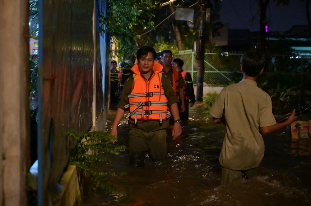 Lực lượng công an, dân quân tự vệ, an ninh trật tự tại cơ sở túc trực xuyên đêm tại các ngã ba, ngã tư ngập nặng để cảnh báo, hướng dẫn người dân không đi vào khu vực nguy hiểm. Ảnh: PHẠM HẢI