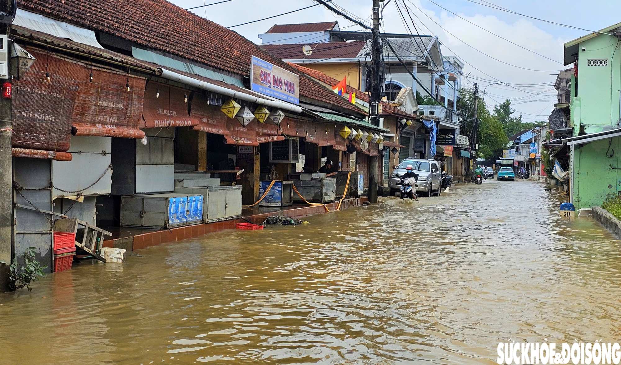 Trước khu vực chợ Bao Vinh, nước sông Hương vẫn dâng cao, tràn lên đường khiến việc đi lại của người dân gặp khó khăn.