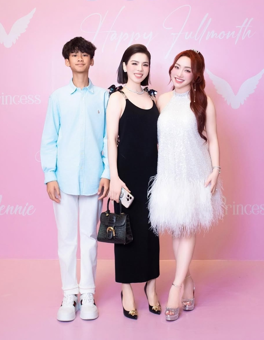 Mẹ con ca sĩ Lệ Quyên tới tiệc mừng thôi nôi của con gái vợ chồng Chi Bảo, Thùy Chang năm ngoái. Ca sĩ chọn đầm và giày của Versace, Kỳ Anh diện sơ mi xanh nhạt của Ralph Lauren, phối quần ống côn và sneakers.