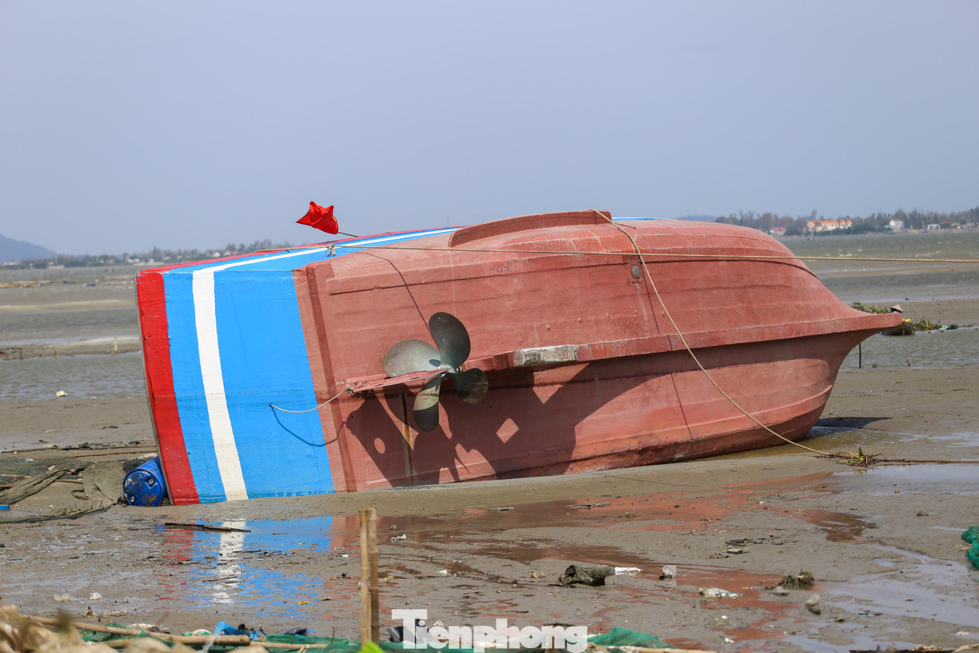 Một tàu bị gió bão đánh úp, vùi một phần dưới bùn. Ảnh: Trương Định