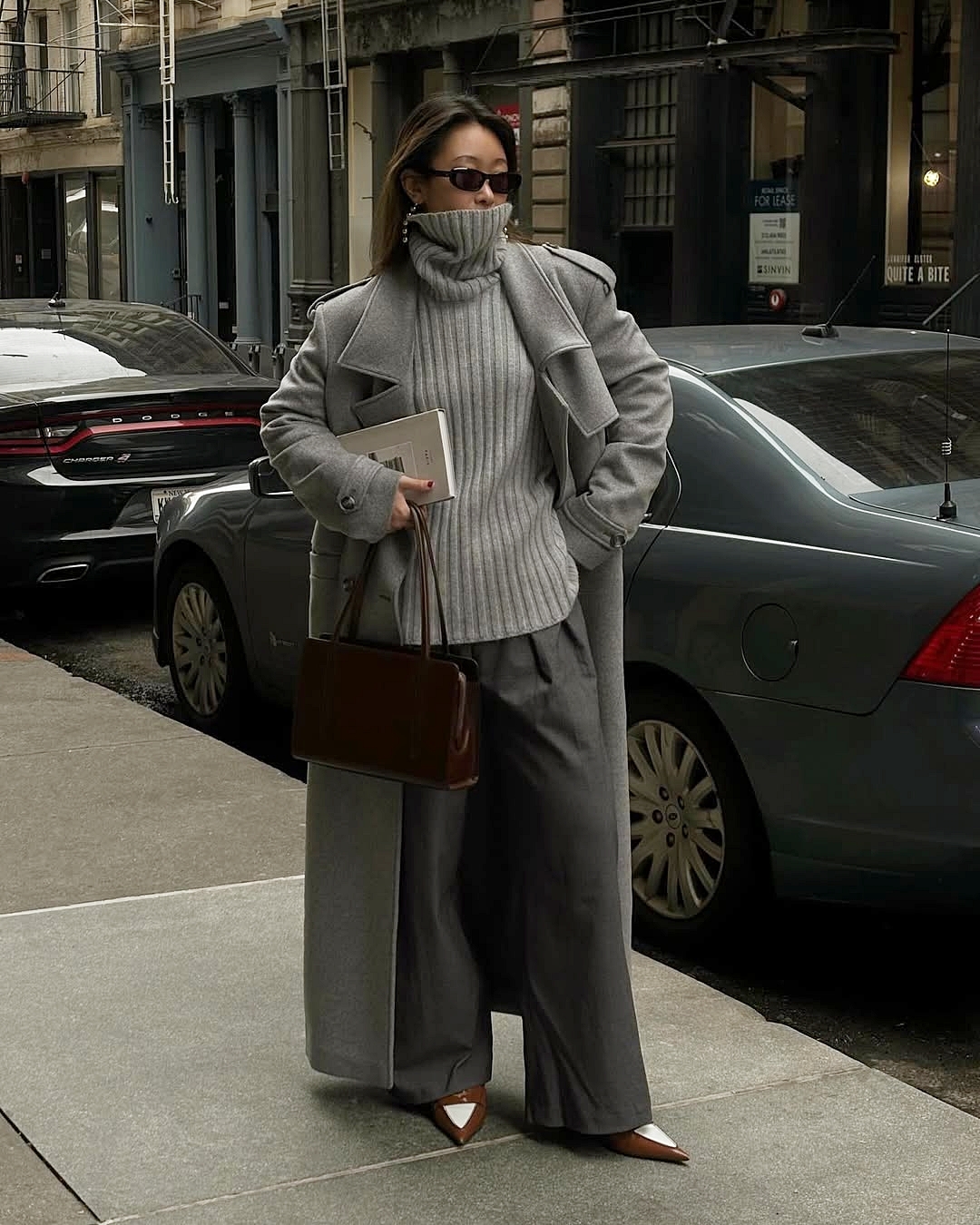 Diện cả bộ màu xám với áo len, quần vải, trench coat, nhấn bằng túi xách và giày đỏ nâu.