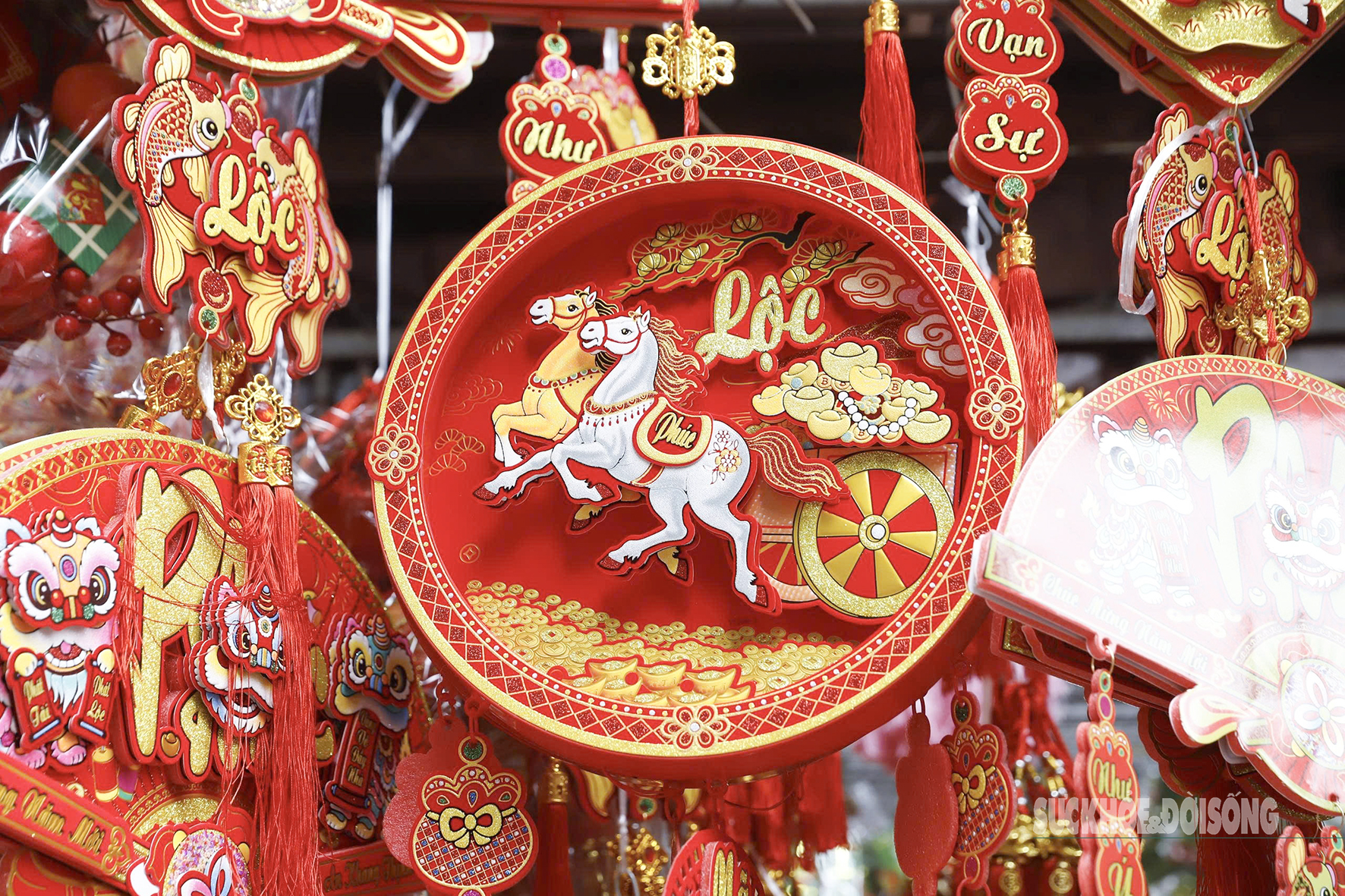 Dây treo, mâm trang trí họa tiết Tết với hình ngựa và chữ Lộc nổi bật giữa rừng phụ kiện đỏ – vàng trên phố Hàng Mã.