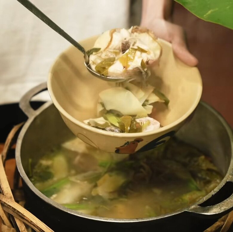 Tô canh nóng hổi được múc ra từ nồi - bên trong là cá, lá chua, rau thơm. Món canh dân dã nhưng tròn vị, chua nhẹ, thơm nức mũi.