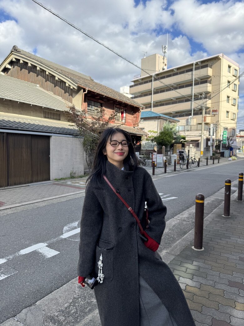 Vào những ngày thời tiết lạnh, một chiếc măng tô dài màu xám đậm, phối cùng túi đeo chéo đỏ và găng tay nổi bật. Đây là kiểu lên đồ đặc trưng của những cô nàng Gen Z yêu sự tinh tế, pha chút nghệ sĩ.