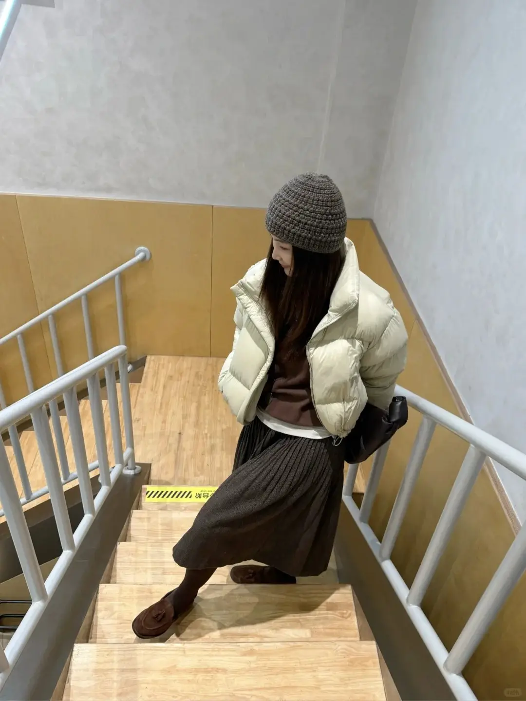 Áo gile phao màu trà sữa phối cùng chân váy xếp ly nâu và giày lười đồng màu mang đến vẻ ngoài nhã nhặn, phù hợp cho cả môi trường công sở lẫn những buổi hẹn hò nhẹ nhàng.