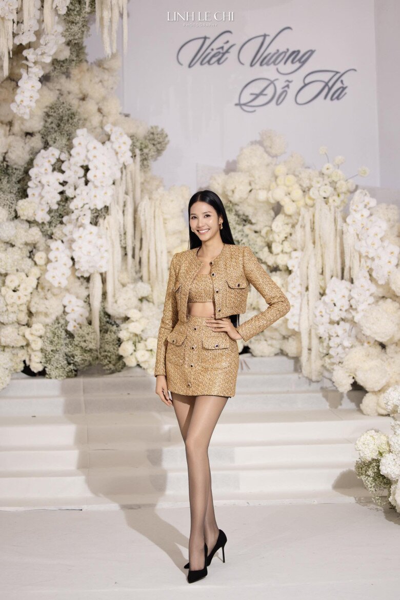 Bộ outfit vàng ánh kim gồm áo khoác ngắn, crop-top và chân váy mini giúp tôn dáng thanh mảnh và phong thái tự tin của Á hậu Hoàng Thùy. Chất liệu bắt sáng giúp tổng thể sang trọng, kết hợp tất da chân và giày cao gót đen tạo vẻ thời thượng, quyền lực mà vẫn tinh tế.