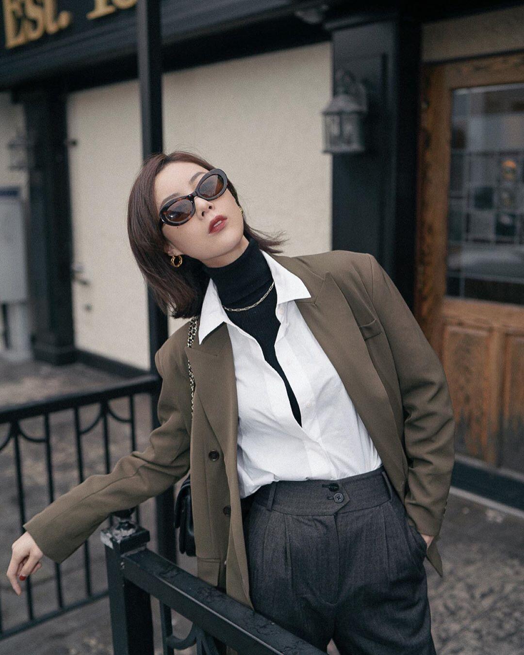 Áo sơ mi trắng kết hợp cùng áo len đen cổ lọ tạo nên sự tương phản thú vị nhưng vẫn hài hòa, tinh tế.