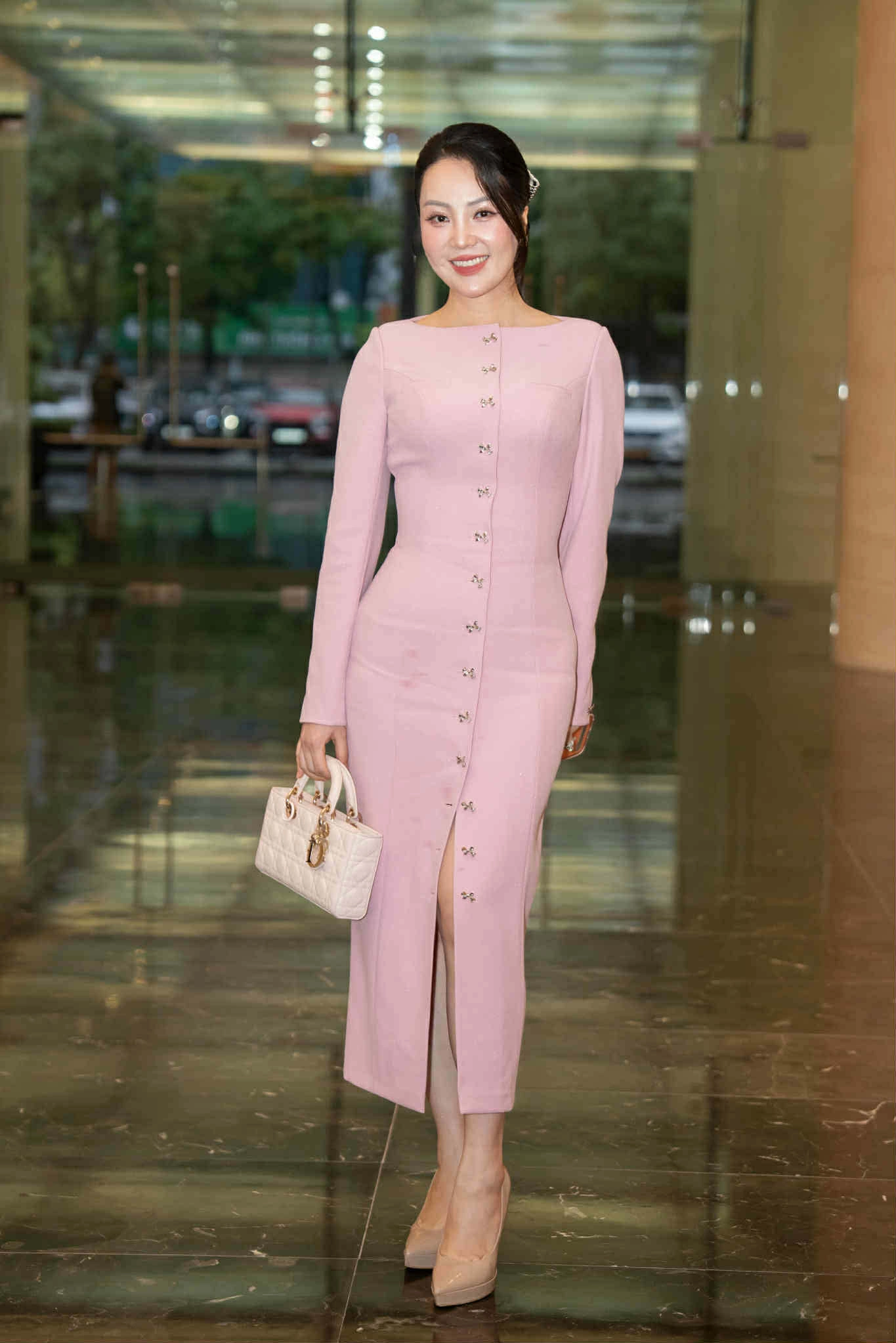 Á hậu Thụy Vân là một trong những khách mời sớm nhất đến chúc mừng đàn em. Cô diện váy hồng pastel dáng midi ôm sát, điểm hàng khuy nhỏ tinh tế, gợi vẻ cổ điển nữ tính. Kết hợp túi Dior trùng kiểu dáng với hoa hậu Lương Thùy Linh và giày nude ton-sur-ton.