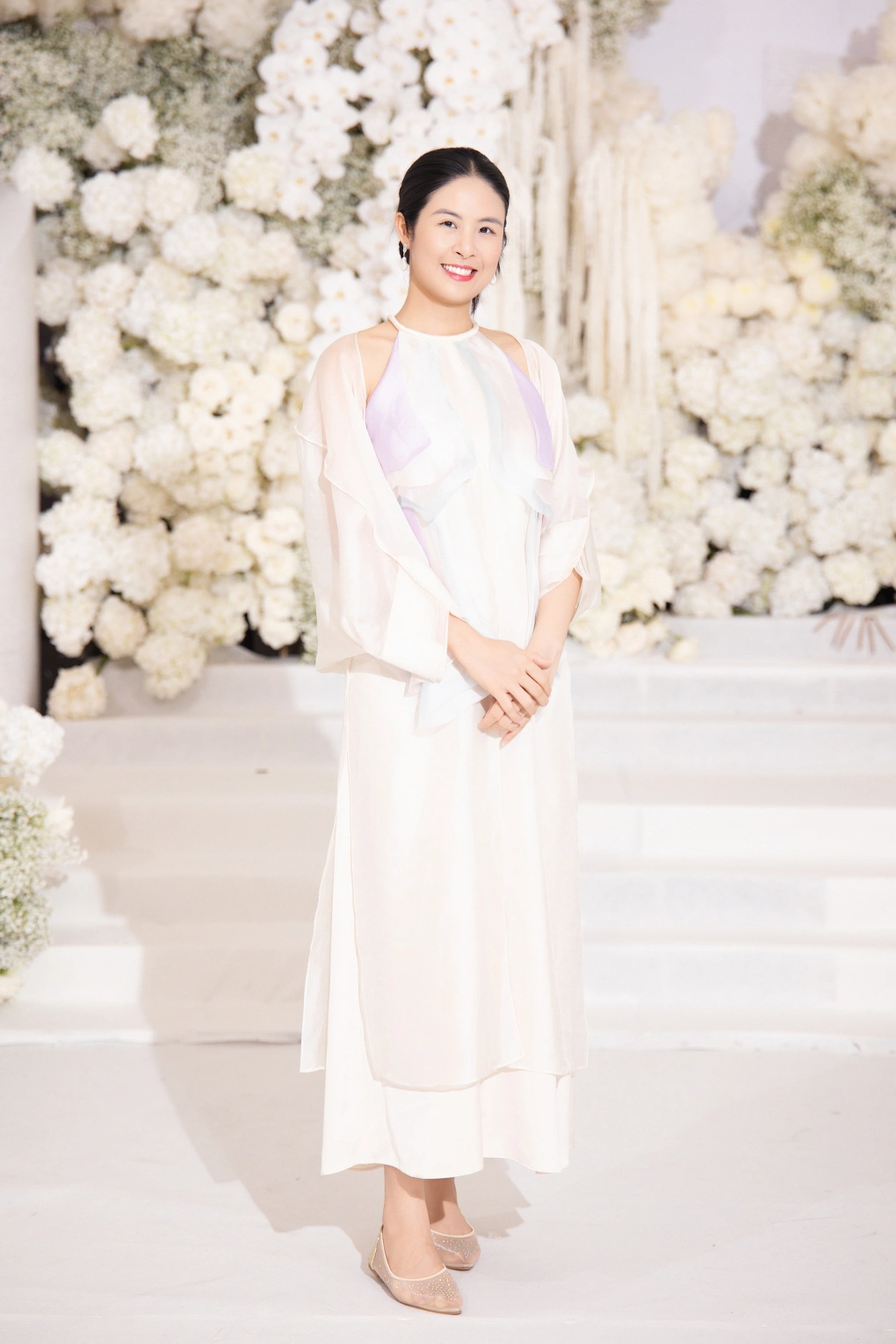 Hoa hậu Ngọc Hân có mối quan hệ thân thiết với Đỗ Thị Hà. Tại tiệc cưới của đàn em, mỹ nhân Hà Thành diện chiếc đầm mang thiết kế tương tự áo dài với gam trắng ánh hồng dịu dàng.