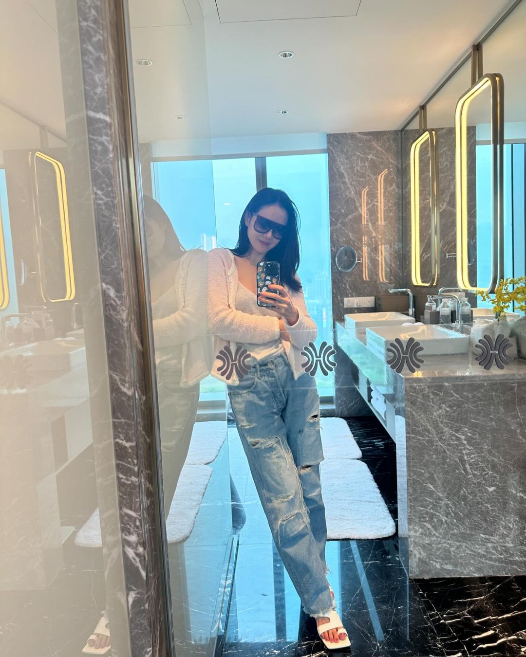 Son Ye Jin cũng rất khéo léo khi phối cardigan theo nhiều cách khác nhau: cài kín như áo thun, khoác hờ lên vai hoặc buộc nhẹ quanh cổ. Cô thường ưu tiên gam màu nhã nhặn như kem, xanh olive hoặc hồng phấn, vừa tôn da vừa giúp tổng thể trông thanh thoát và sang nhẹ nhàng.