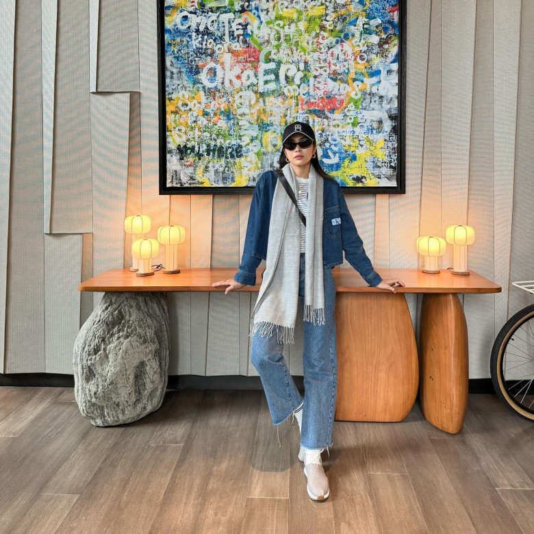 Hà Tăng khoe phong thái năng động với công thức denim-on-denim cực chuẩn. Áo khoác denim phối cùng quần jeans ống suông tạo sự đồng điệu phóng khoáng. Chiếc khăn len xám dài mang lại vẻ mềm mại, cân bằng với phụ kiện như mũ lưỡi trai đen và kính râm bản lớn tạo hiệu ứng “cool girl”.