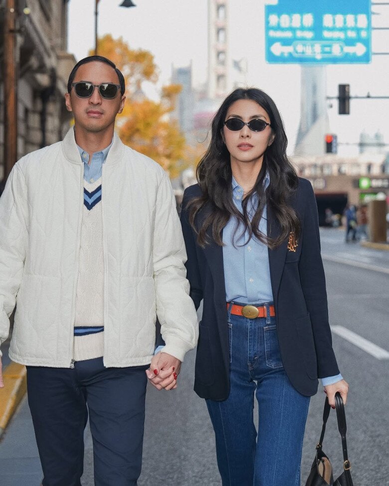 Xuất hiện bên cạnh ông xã, bà mẹ 3 con mang đậm tinh thần preppy sang trọng. Blazer navy phối cùng sơ mi xanh baby, điểm xuyết chiếc thắt lưng cam nổi bật. Quần denim xanh đậm giúp cân bằng tổng thể, vừa trẻ trung vừa cổ điển. 