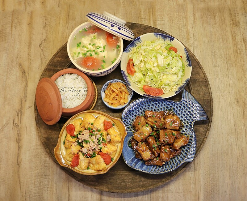 Mâm cơm này gồm các món: Sườn xào chua ngọt, đậu phụ rán sốt cà chua, bắp cải xào, canh đậu trứng