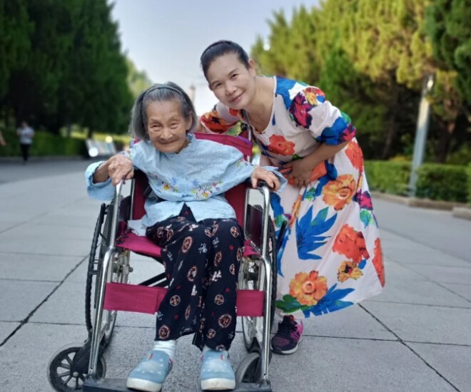 Bà Li Kuiliang đẩy xe lăn đưa mẹ ra ngoài.