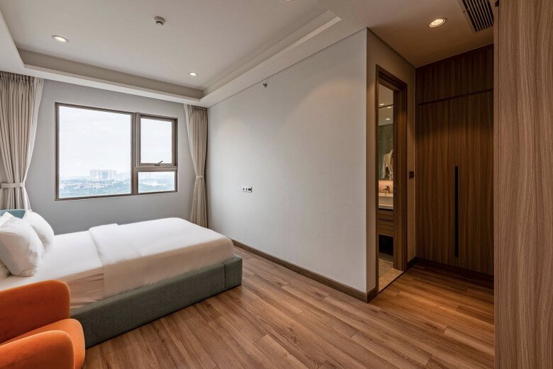 Phòng của mẹ và em nơi mình có thể ngắm dòng sông lững lờ mỗi sáng thức dậy, nàng hậu tâm sự. Căn phòng được thiết kế đơn giản với giường màu pastel, ghế cam nổi bật và sàn gỗ ấm áp. Có một khoảng rộng bên dưới để em bé có thể chơi dưới sàn.