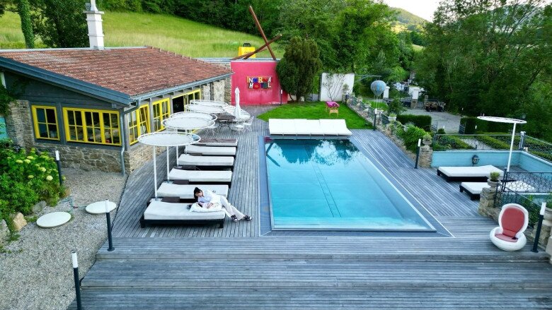 Không gian nghỉ dưỡng bên ngoài căn biệt thự cổ tại Áo – nơi Á hậu từng sống lúc mới sinh con. Hồ bơi trong xanh giữa sân gỗ rộng lớn, xung quanh là hàng ghế tắm nắng, ô che màu trắng, ghế thư giãn, tất cả toát lên cảm giác thư thái, biệt lập với thế giới bên ngoài.