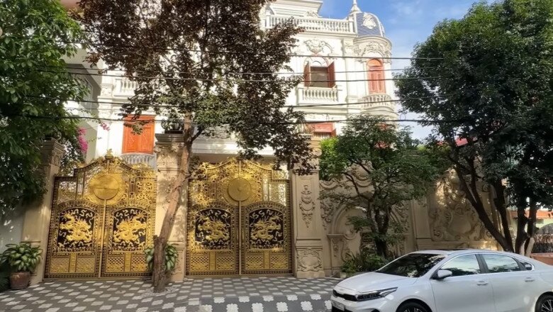 Toàn cảnh mặt tiền biệt thự Cẩm Nhung của em gái Long Nhật, với phong cách châu Âu cổ điển, trần cao, lan can trắng, và những ô cửa gỗ nổi bật. Cổng biệt thự mạ vàng ấn tượng giữa khu nhà giàu, thiết kế chạm rồng tinh xảo, mang đậm phong cách hoàng gia.