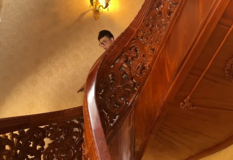 Cầu thang gỗ xoắn uốn lượn mềm mại, lan can điêu khắc công phu, là điểm nhấn kiến trúc nổi bật của biệt thự.