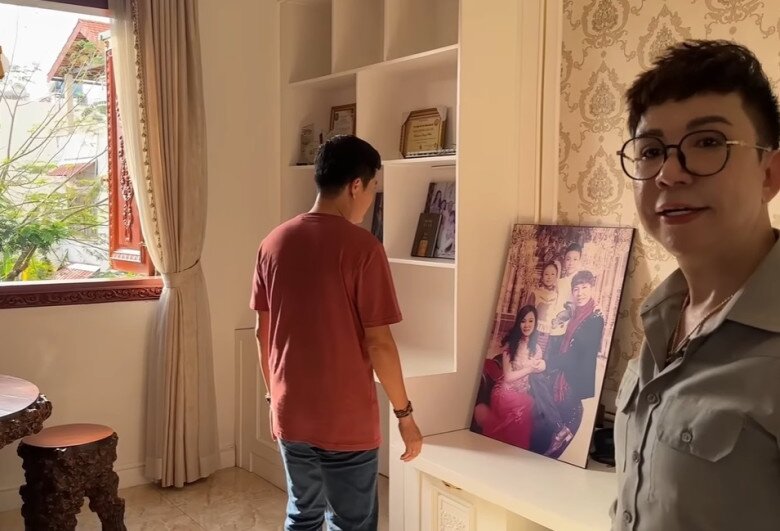 Đây là phòng của Long Nhật, có nhiều bức ảnh của vợ con. Trong phòng có một bộ bàn ghế gỗ bên khung cửa, ánh sáng tự nhiên tràn ngập từ cửa sổ.