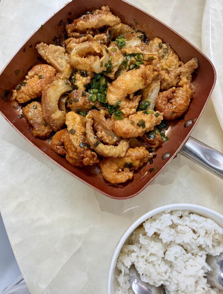 Bên cạnh món salad đầy sắc màu, Kelvin Khánh còn đứng sau nhiều món ăn hấp dẫn khác làm cho vợ. Một chảo đầy món chiên giòn vàng ruộm, được sốt hành lá thơm phức, ăn kèm với cơm trắng nóng hổi. Khởi My đùa vui: “Giựt bung cái nách luôn shop ơi. Đầu bếp nhà mình mà, ha ha ha”.