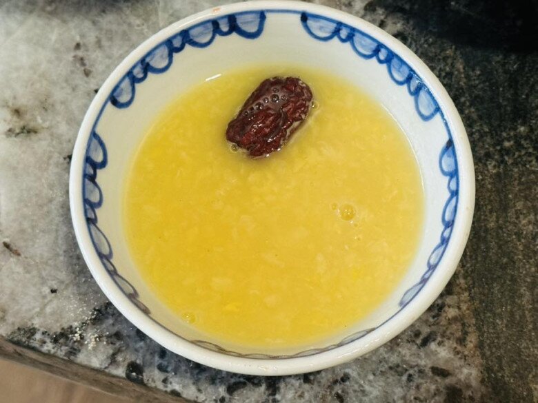 Món chè đậu xanh đánh sánh mịn, được điểm xuyết bằng một quả táo tàu đỏ thẫm, gợi lên sự ấm áp và bình yên trong tâm hồn.