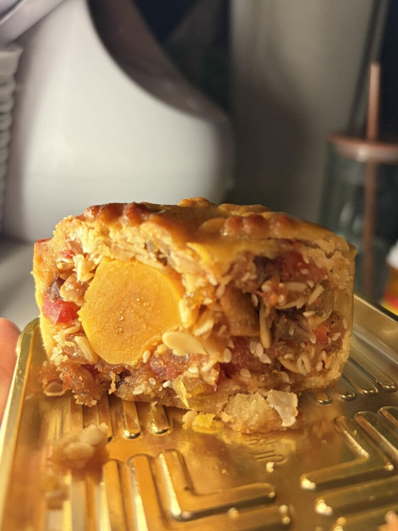 Chiếc bánh được cắt đôi để lộ phần nhân thập cẩm cực kỳ chất lượng bên trong: Qà quay, vi cá, hạt sen, jambon, trứng muối… tất cả hoà quyện thơm lừng. Chỉ nhìn thôi cũng đủ thấy công phu và sự tỉ mỉ.