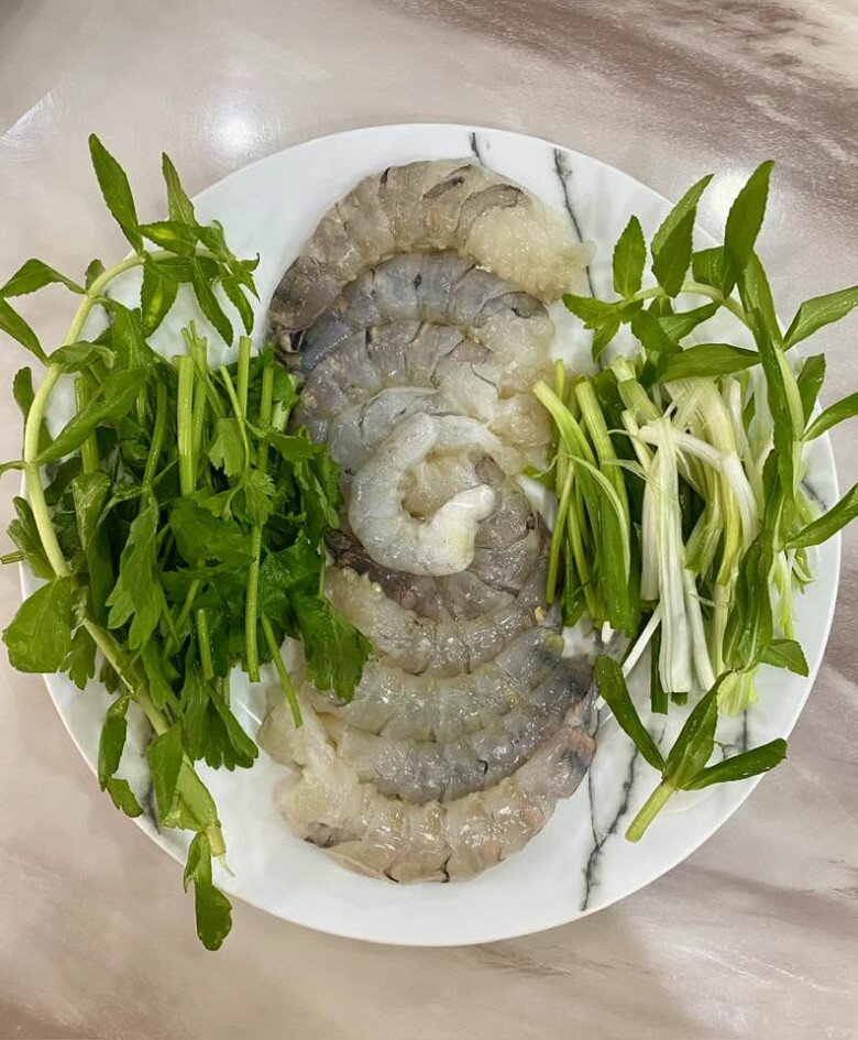 Bên cạnh là tôm sú lột vỏ tươi rói, mực ống cắt khoanh, cùng nhiều loại rau xanh như rau cải, rau cần, tần ô... Tất cả sẵn sàng cho một nồi lẩu cá khoai nghi ngút khói - món đặc sản nổi tiếng của đất cảng Hải Phòng, quê chồng Vy Oanh.