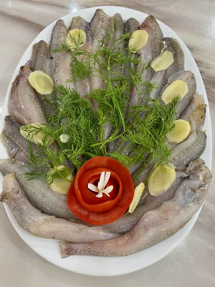 Một mâm nguyên liệu được bày biện đẹp mắt gồm cá khoai tươi rói xếp đều, điểm xuyết lát gừng tươi, thì là và hoa cà chua tỉa xinh xắn.