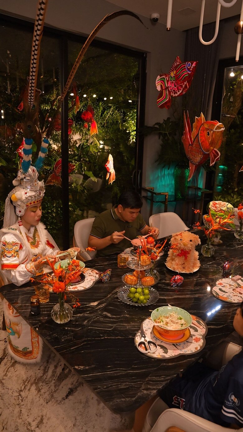 Sắc cam đỏ của những món đồ decor đối lập hài hòa với không gian xanh từ khu vườn bên ngoài. Trên bàn ăn, từng chiếc đĩa, ly thủy tinh, hoa tươi và nến được bài trí chỉn chu. 