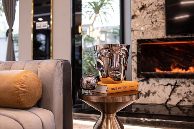 Chi tiết nội thất trong nhà như bàn sofa với tượng trang trí kim loại và sách thời trang thể hiện gu thẩm mỹ hiện đại, tinh tế của gia chủ.