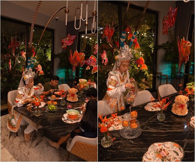 Góc bàn ăn được gia đình nàng hậu trang hoàng rực rỡ với lồng đèn cá chép treo lơ lửng, hoa tươi màu cam nổi bật trên nền bàn đá đen sang trọng. Những chiếc bánh Trung thu được đặt ngay ngắn bên cạnh mâm ngũ quả, tạo nên không gian ấm cúng và truyền thống.