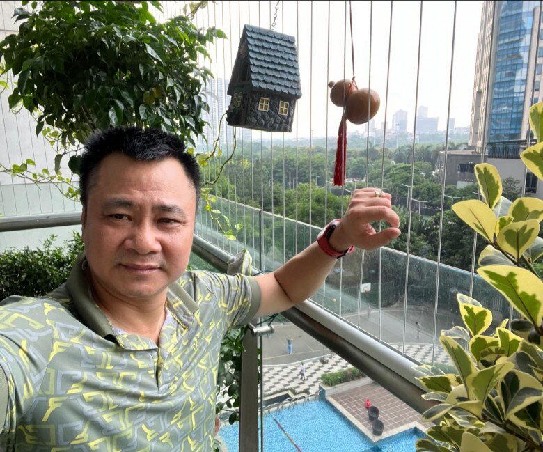 Nam nghệ sĩ tạo dáng bên ban công tầng cao, được treo ngôi nhà decor và hồ lô phong thủy - những chi tiết nhỏ tạo nên sự thư thái, gần gũi cho không gian sống.