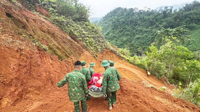 Lực lượng chức năng thay phiên nhau khiêng cáng, bảo đảm an toàn cho sản phụ.