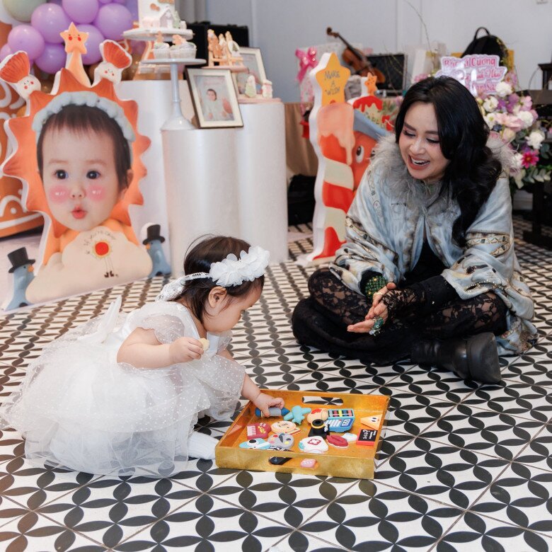 Nữ NSND hạnh phúc khi bé Bao Bao bóc chiếc micro trong mâm thôi nôi.