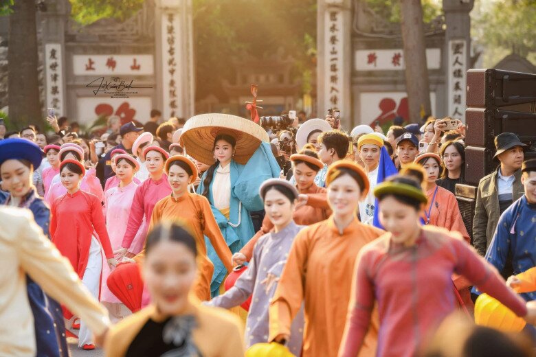 Lọ Lem diện cổ phục màu xanh và vàng, đội nón ba tầm đầy nổi bật giữa đám đông diễu hành.