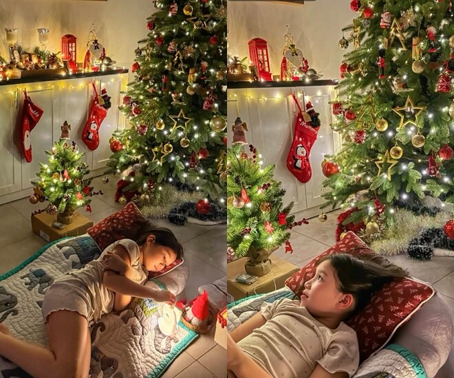 Con gái Hà Anh mang chăn gối ra cạnh cây thông nằm vì quá háo hức chờ đón Giáng sinh.