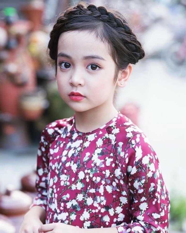 Cô bé có đôi mắt to trò, sống mũi cao, miệng chúm chím.