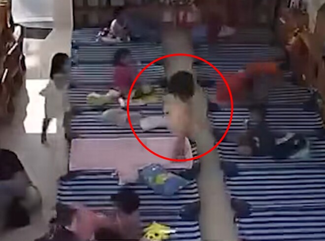 Bé gái tự trải chăn khi đi ngủ trưa ở lớp.